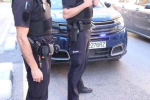 Dos agentes de la Policía Nacional junto a un coche patrulla